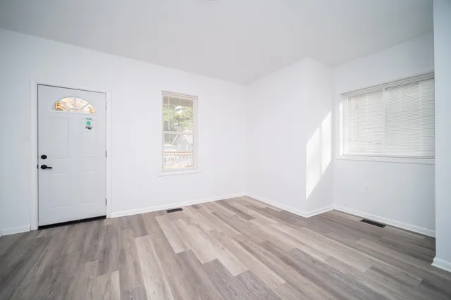 an empty room with wooden floor and windows