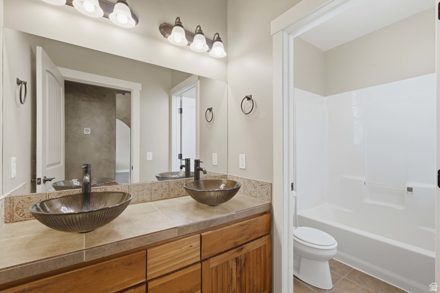 2567 West Rim Rock Drive Stockton, UT 84071 - Photo 27 of 64 Double vanity featuring vessel sinks with dark bronze fixtures, tile countertops, and wood-finish cabinetry