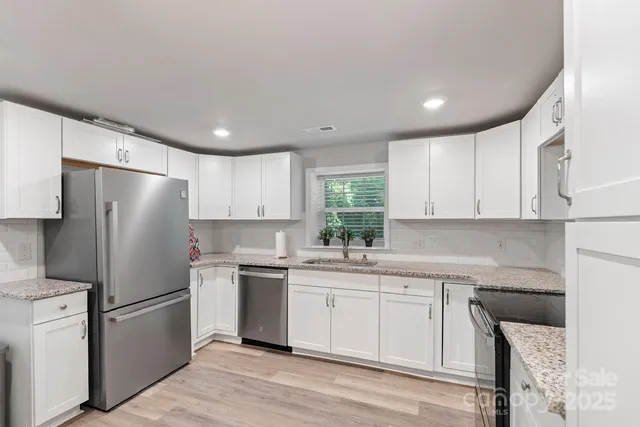 a kitchen with a sink a refrigerator and white cabinets
