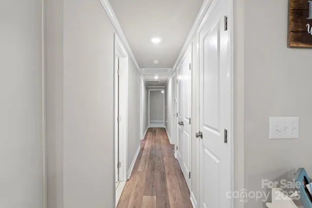 a view of a hallway with wooden floor and a bathroom