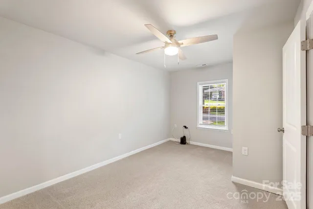 an empty room with a window and a fan
