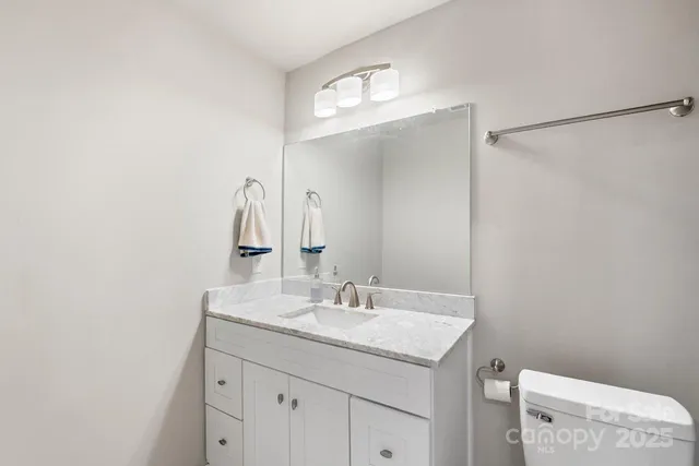a bathroom with a granite countertop sink a toilet and a mirror
