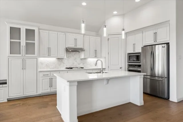 a kitchen with stainless steel appliances granite countertop a sink refrigerator and cabinets
