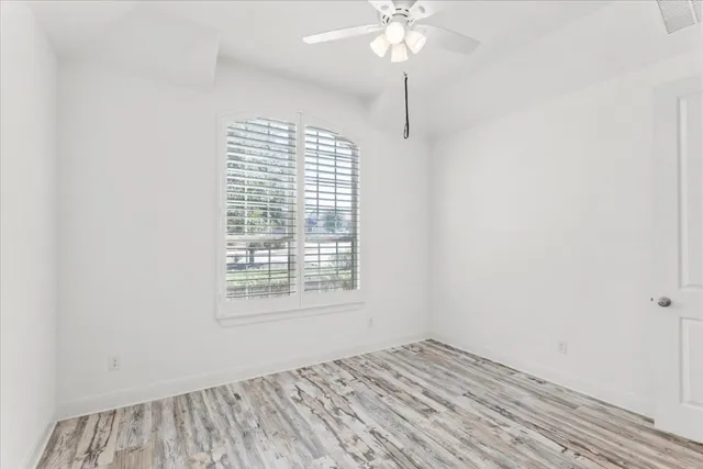 an empty room with a chandelier fan and windows