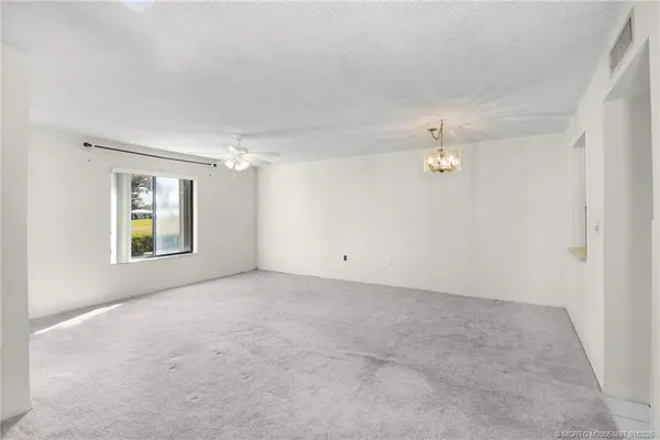 an empty room with windows and chandelier fan