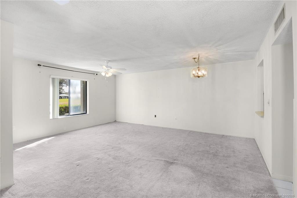 5303 Southeast Miles Grant Road, Unit L101 Stuart, FL 34997 - Photo 3 of 54 an empty room with windows and chandelier fan