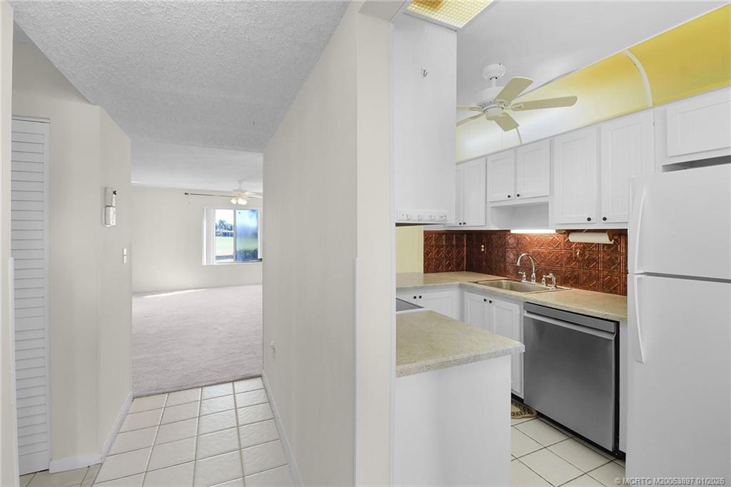 5303 Southeast Miles Grant Road, Unit L101 Stuart, FL 34997 - Photo 9 of 54 a kitchen with white cabinets and appliances