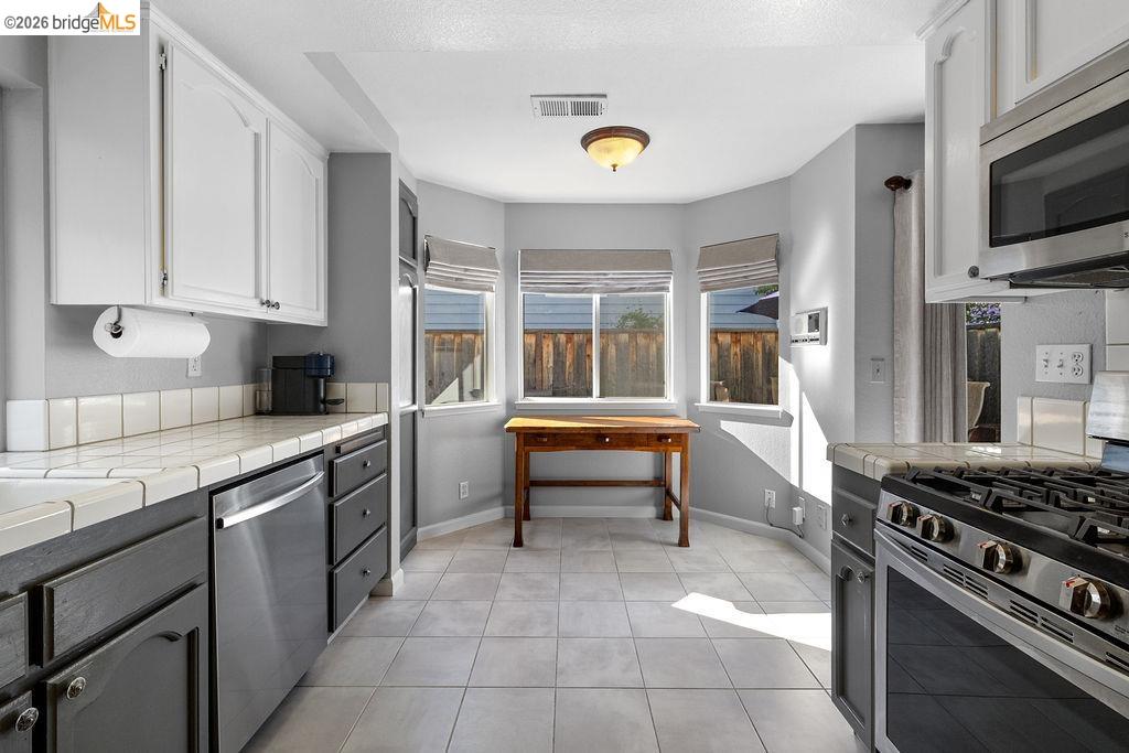 724 Winterside Circle San Ramon, CA 94583 - Photo 6 of 43 Kitchen featuring two-tone cabinetry with white upper and dark lower cabinets, stainless steel appliances, and tiled countertops