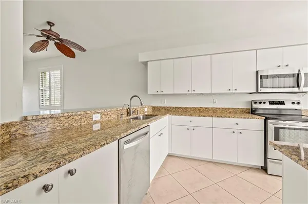 a kitchen with granite countertop white cabinets and white appliances