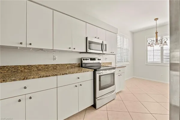 a kitchen with granite countertop white cabinets and white appliances