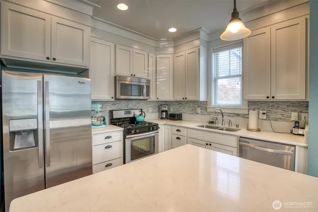 a kitchen with stainless steel appliances granite countertop a refrigerator a sink a stove and white cabinets
