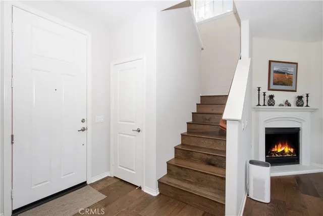 a view of an empty room with wooden floor fireplace and staircase