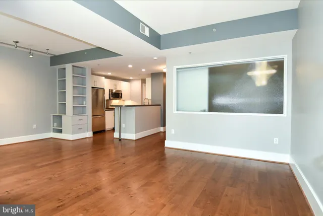 a view of an empty room with a window and wooden floor
