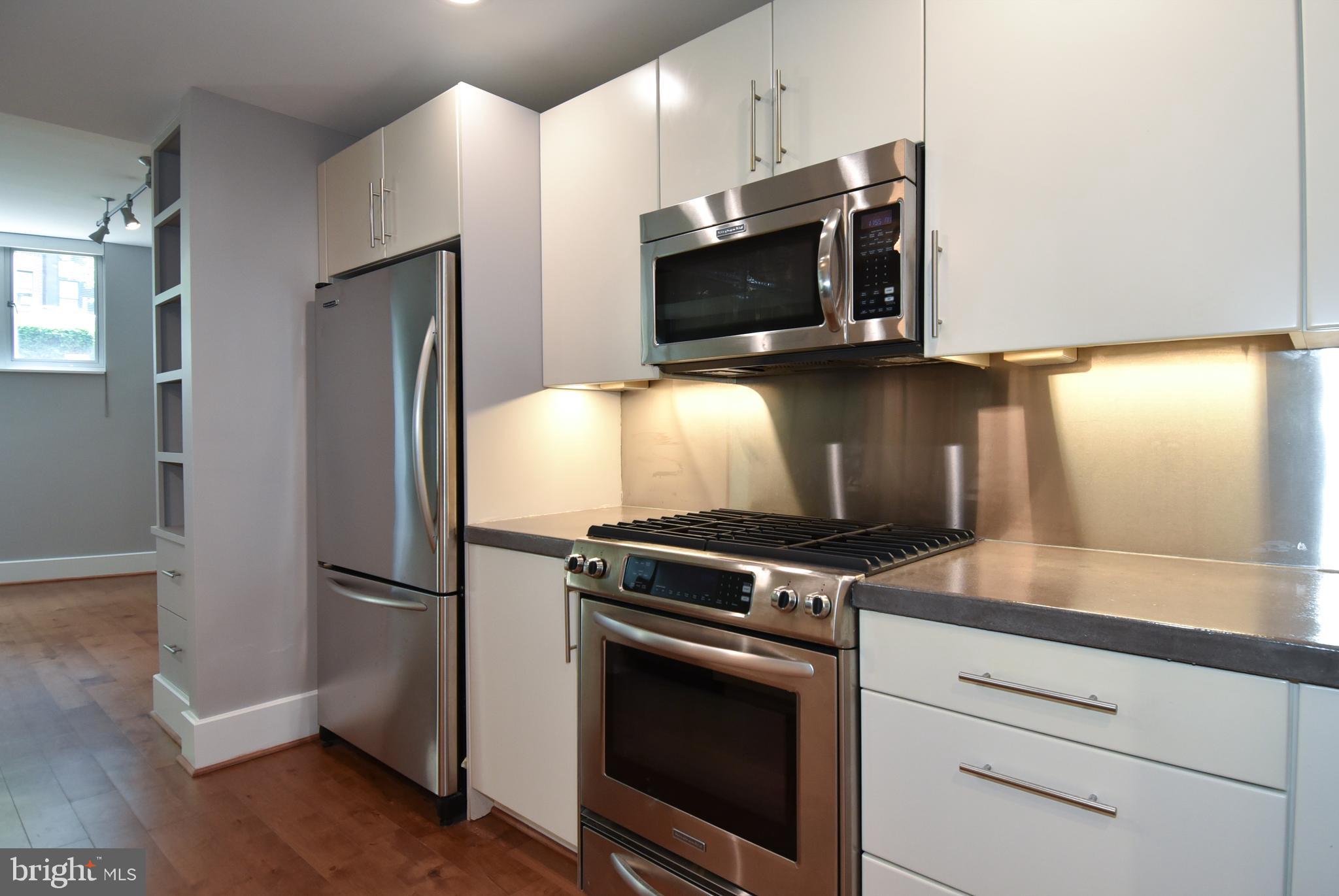 2100 11th Street Northwest, Unit G02 Washington, DC 20001 - Photo 20 of 36 a kitchen with granite countertop white cabinets stainless steel appliances and wooden floor