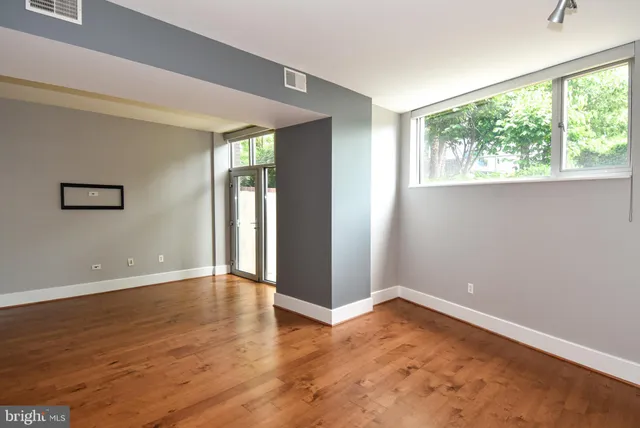 a view of an empty room with wooden floor and a window