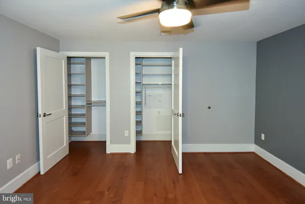 an empty room with wooden floor chandelier fan and windows