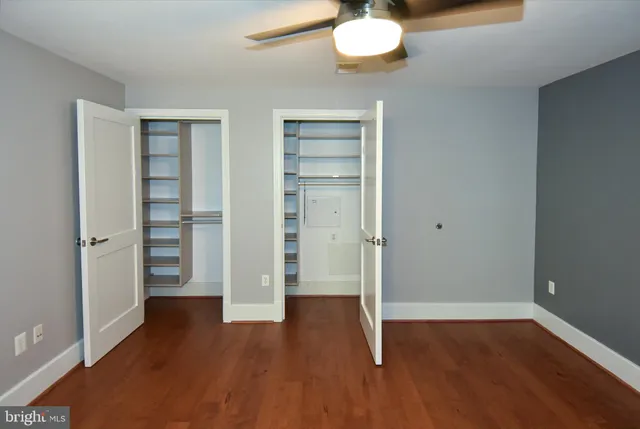 an empty room with wooden floor chandelier fan and windows