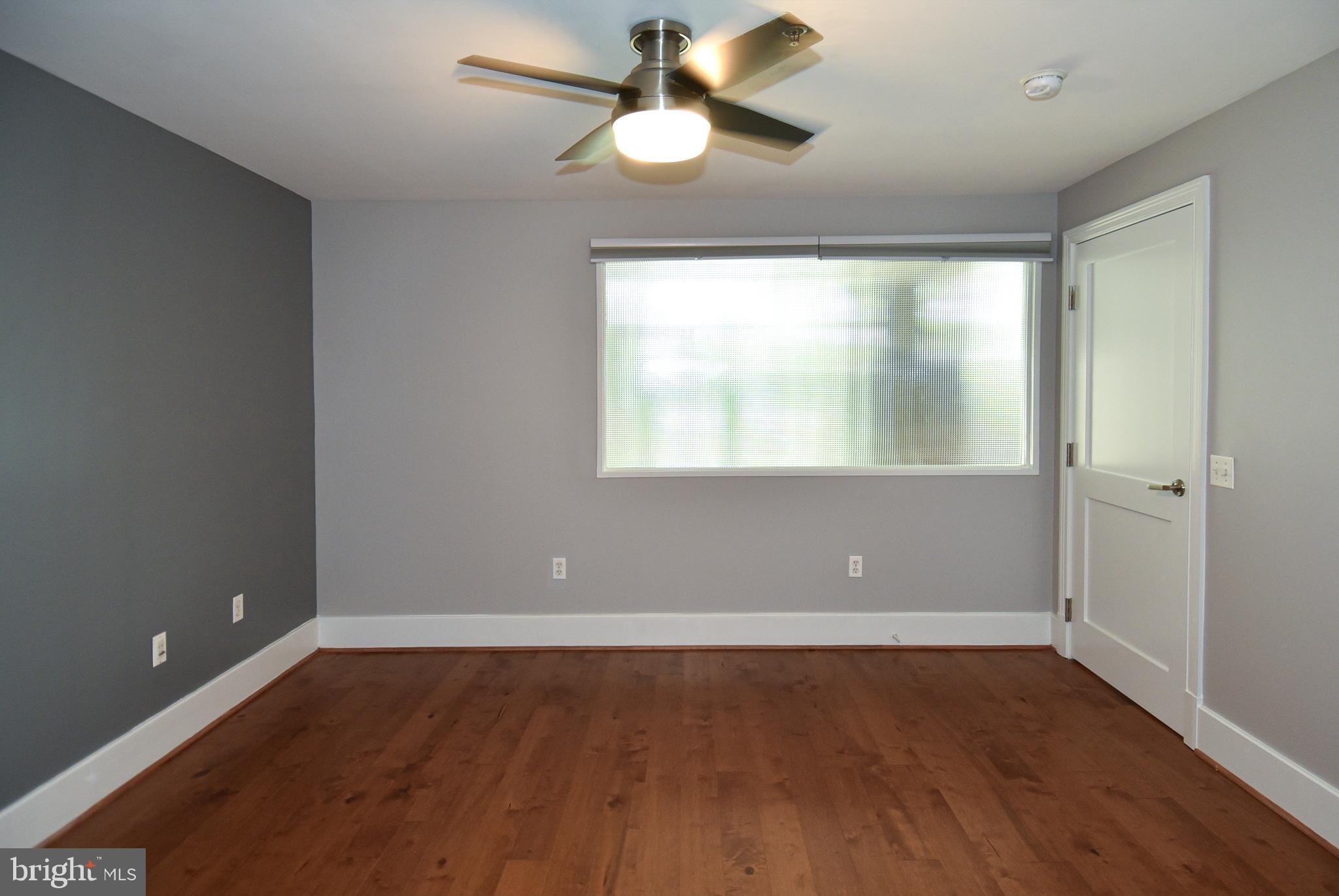 2100 11th Street Northwest, Unit G02 Washington, DC 20001 - Photo 30 of 36 an empty room with wooden floor chandelier fan and windows