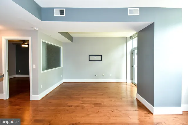 a view of an empty room with wooden floor and a window