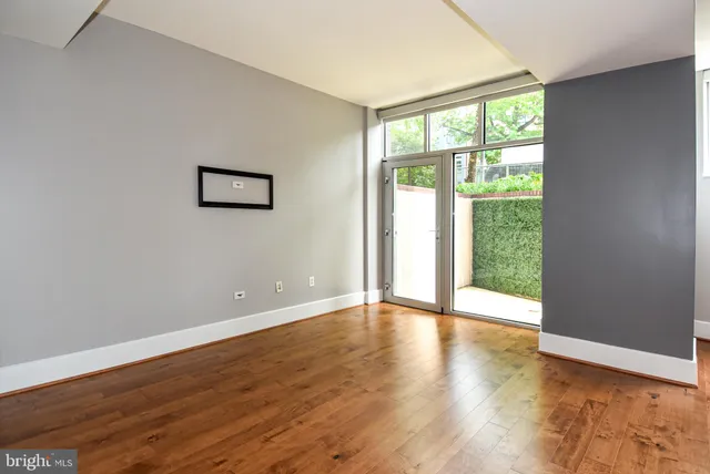 a view of an empty room with wooden floor and windows