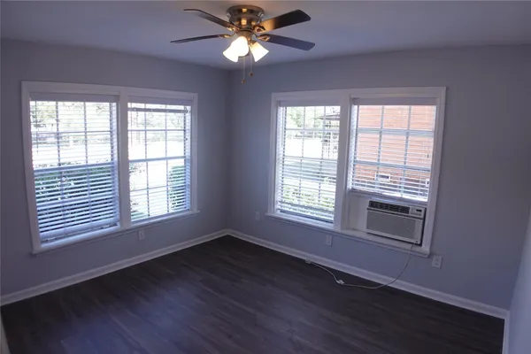 a view of an empty room with wooden floor and a window
