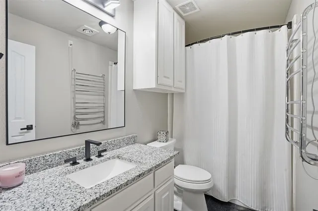 a bathroom with a granite countertop sink toilet and a mirror