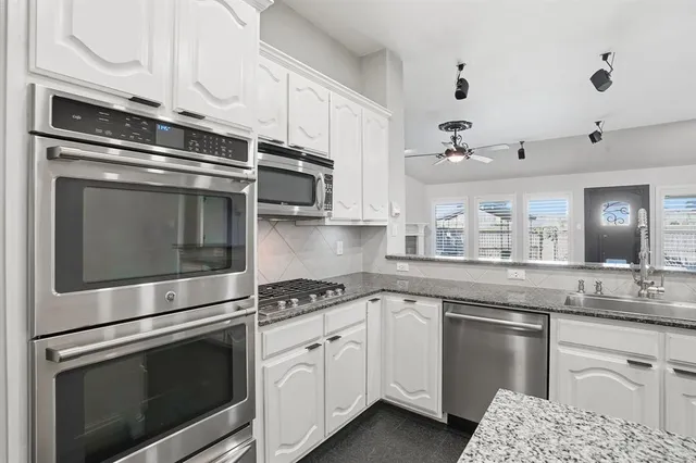 a kitchen with granite countertop white cabinets and a sink
