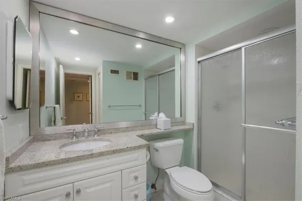 a bathroom with a granite countertop sink toilet a large mirror and shower