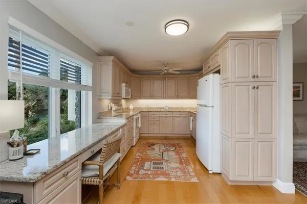 a kitchen with granite countertop a refrigerator a sink and dishwasher a stove top oven with wooden floor