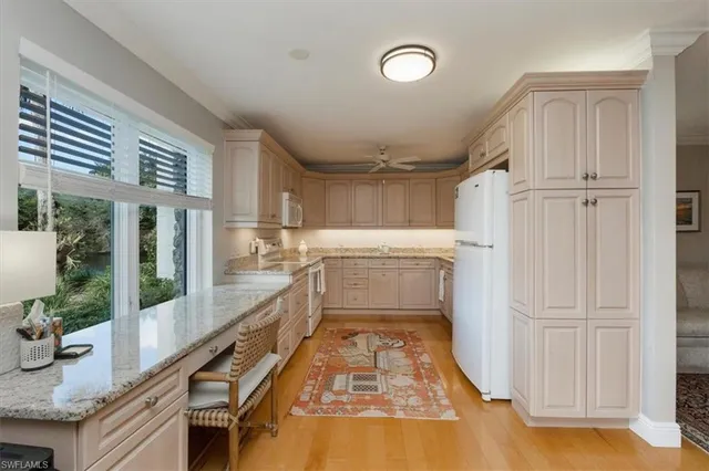 a kitchen with granite countertop a refrigerator a sink and dishwasher a stove top oven with wooden floor