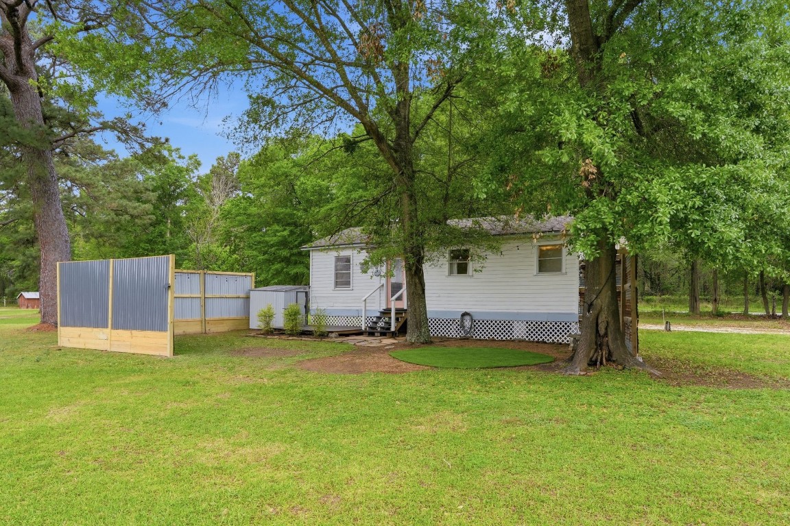 11757 Calvary Road Willis, TX 77318 - Photo 23 of 33 Back view of the home showing a large yard,trees, and a peaceful, open setting.