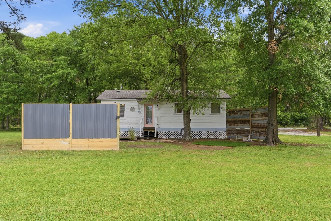 11757 Calvary Road Willis, TX 77318 - Photo 24 of 33 A look at the back of the home surrounded by open space and shaded by trees.
