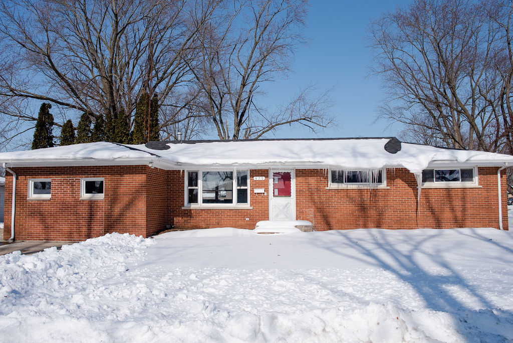 a front view of a house with a yard covered in snow