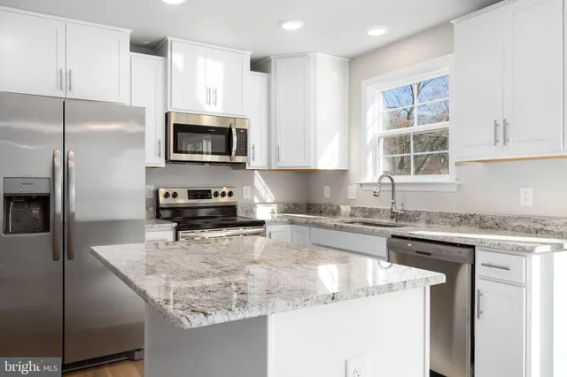 a kitchen with kitchen island granite countertop a sink stove and refrigerator