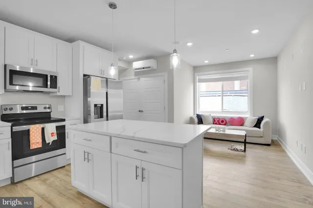 a living room with stainless steel appliances kitchen island granite countertop a stove a sink a refrigerator and white cabinets with wooden floor