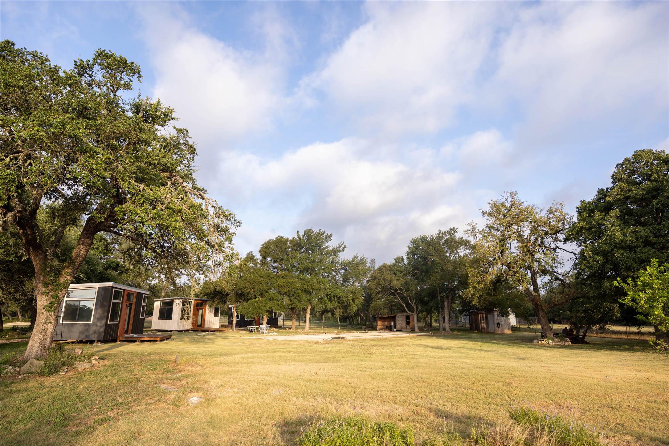 240 Lanier Ranch Road, Unit B Driftwood, TX 78619 - Photo 14 of 26 A verdant retreat offers a collection of modern tiny homes nestled among mature trees on a sprawling grassy lot.