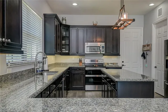 a kitchen with stainless steel appliances granite countertop a sink stove and refrigerator