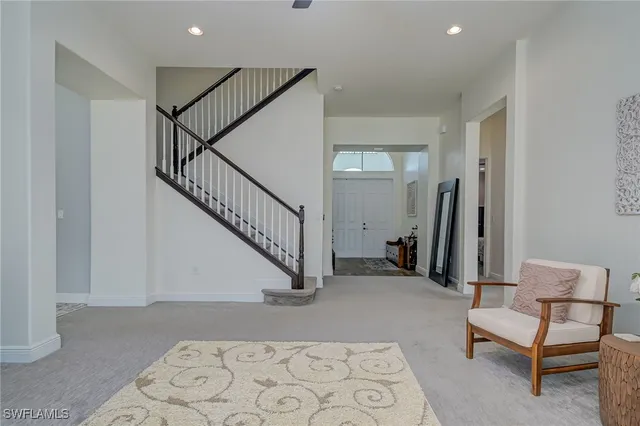 a view of a hallway with stairs and a livingroom with furniture