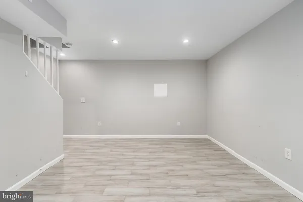 a view of an empty room with wooden floor and a ceiling fan