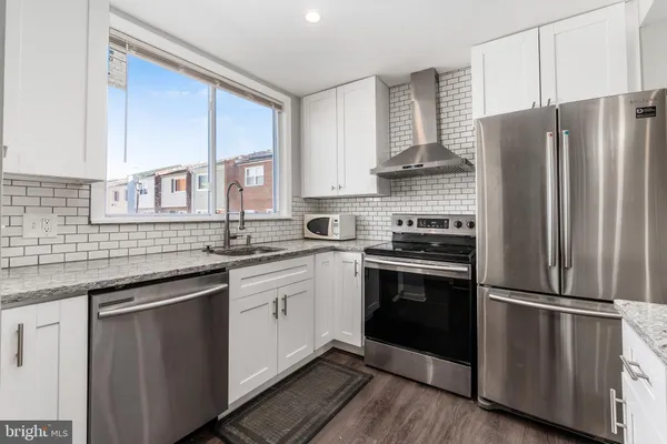 a kitchen with kitchen island a refrigerator and a stove top oven