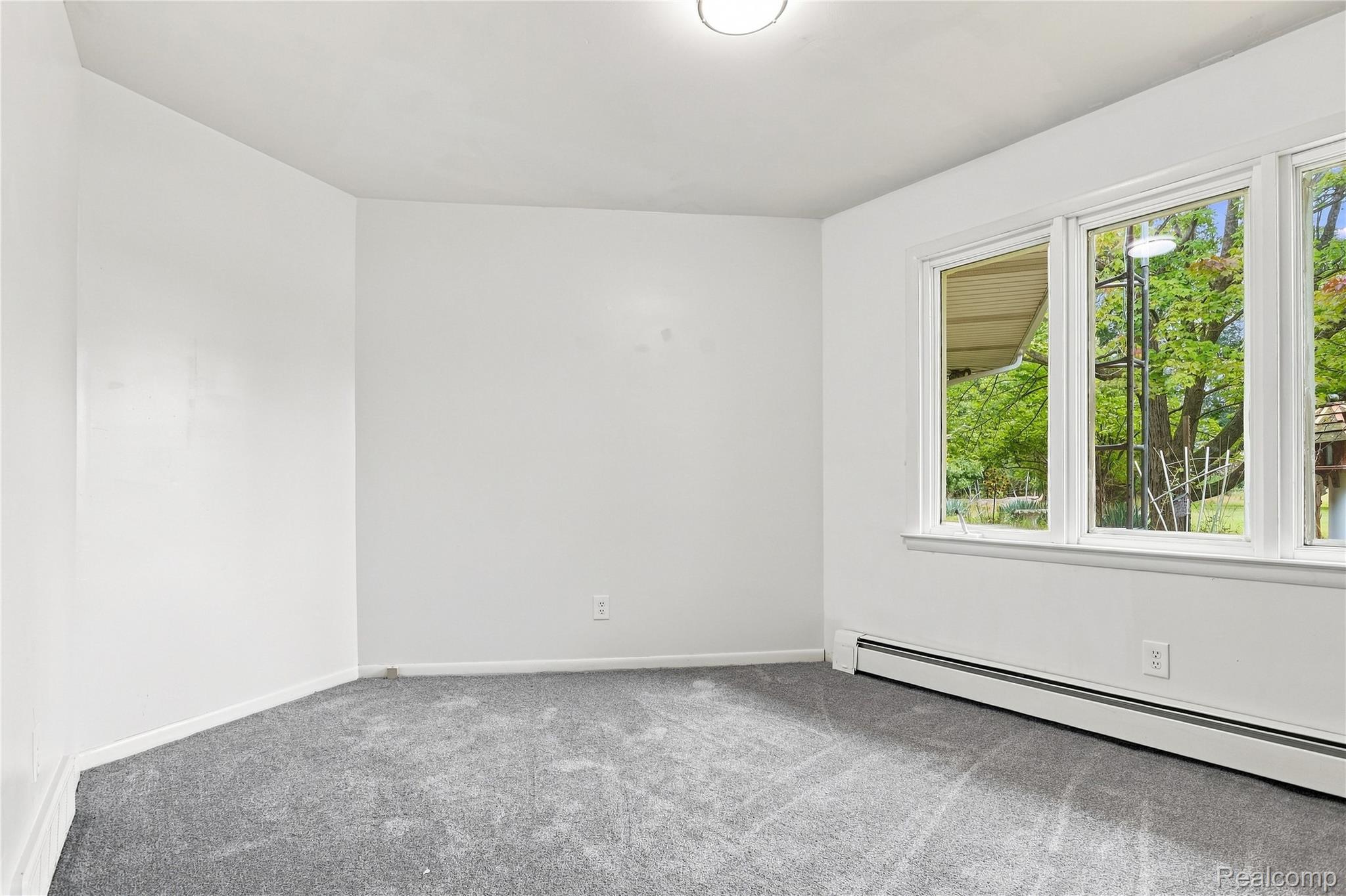 7386 Dean Road Fenton, MI 48430 - Photo 33 of 64 Gray carpeted room featuring white walls, a flush-mount ceiling light, and a series of three windows