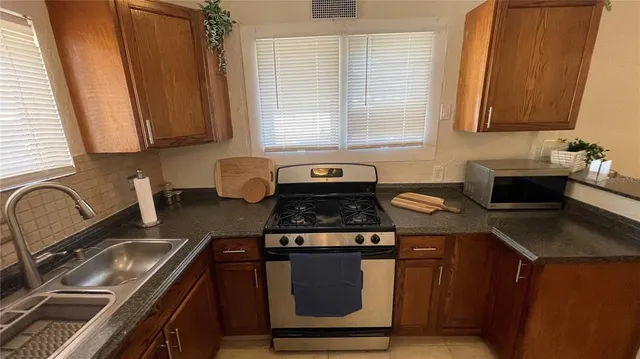 a kitchen with stainless steel appliances granite countertop a stove a sink and a microwave