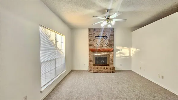 an empty room with chandelier fan and windows