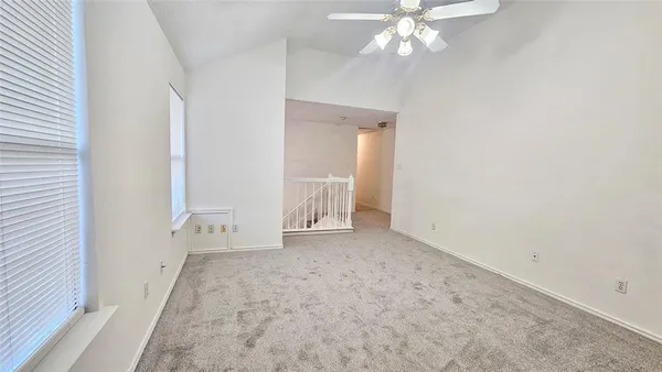 an empty room with chandelier fan and windows