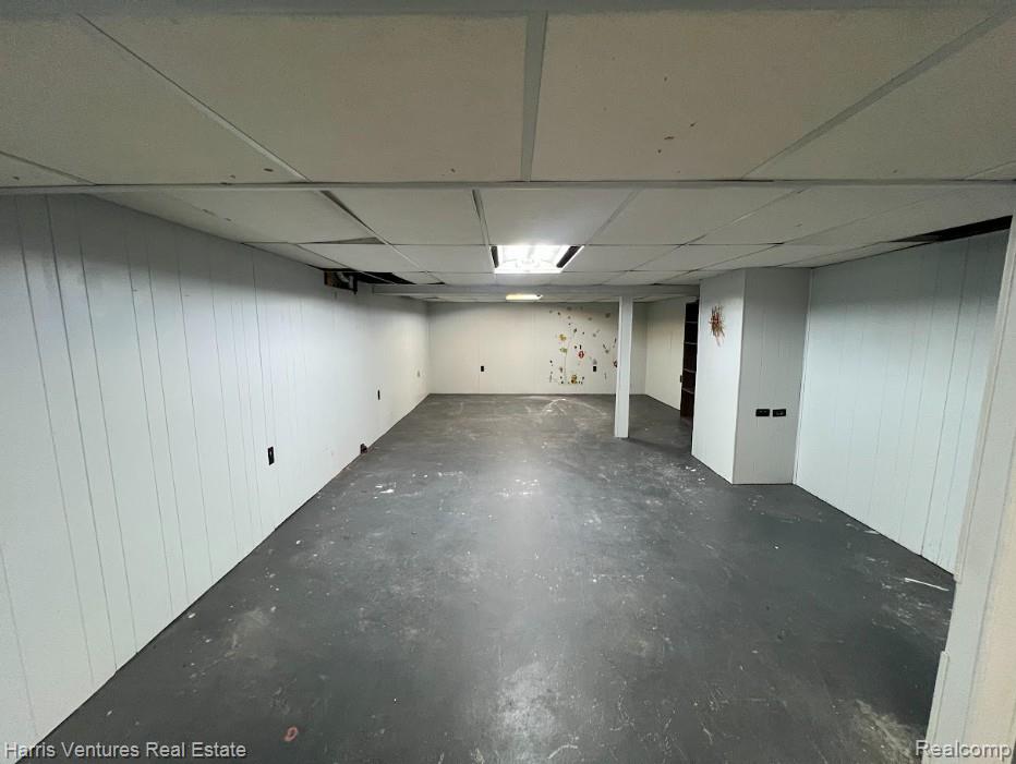 28482 Sutherland Avenue Warren, MI 48088 - Photo 21 of 25 Spacious room featuring white vertical paneling, painted concrete flooring, and a drop ceiling with recessed lighting