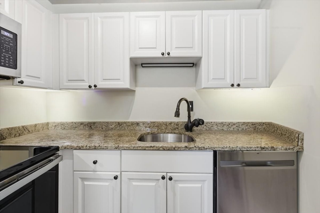 65 Glen Road, Unit H1 Brookline, MA 02445 - Photo 14 of 39 a kitchen with granite countertop white cabinets and a sink