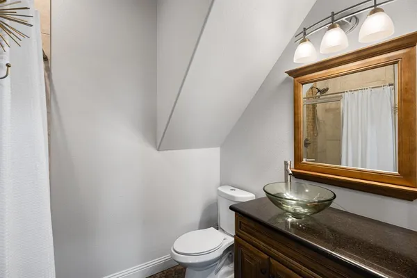 a bathroom with a granite countertop sink and a toilet