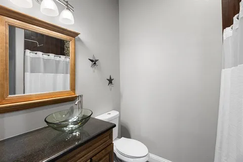 a bathroom with a granite countertop toilet and a sink