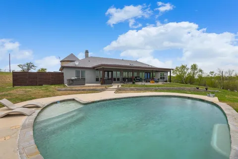a view of a swimming pool is middle in the backyard