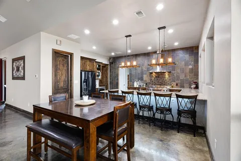 a kitchen with a dining table chairs and wooden floor